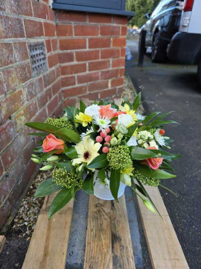 Peach Meadow Delight - A fresh and uplifting arrangement with soft peach tones, gentle creams, and vibrant greenery. Designed in a low, natural style, it has a relaxed, garden-picked feel with a lovely balance of colour and texture. The subtle pops of warm hues add charm and br