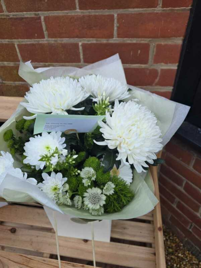 Serenity - A calm and elegant bouquet featuring a refined palette of crisp whites and fresh green accents. Designed with a soft, rounded shape, this arrangement highlights gentle textures and a clean, minimalist style. Subtle greenery adds depth and contrast while maintaining a peaceful, understated look. Wrapped in soft tones for a polished finish, it’s perfect for sympathy gestures, thoughtful gifts, or bringing a sense of tranquility to any space.
